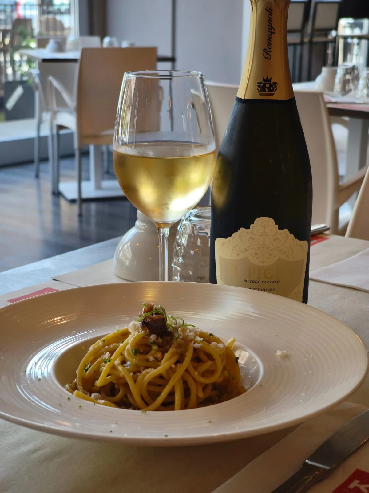 Un piatto di pasta accompagnato da un calice di vino bianco